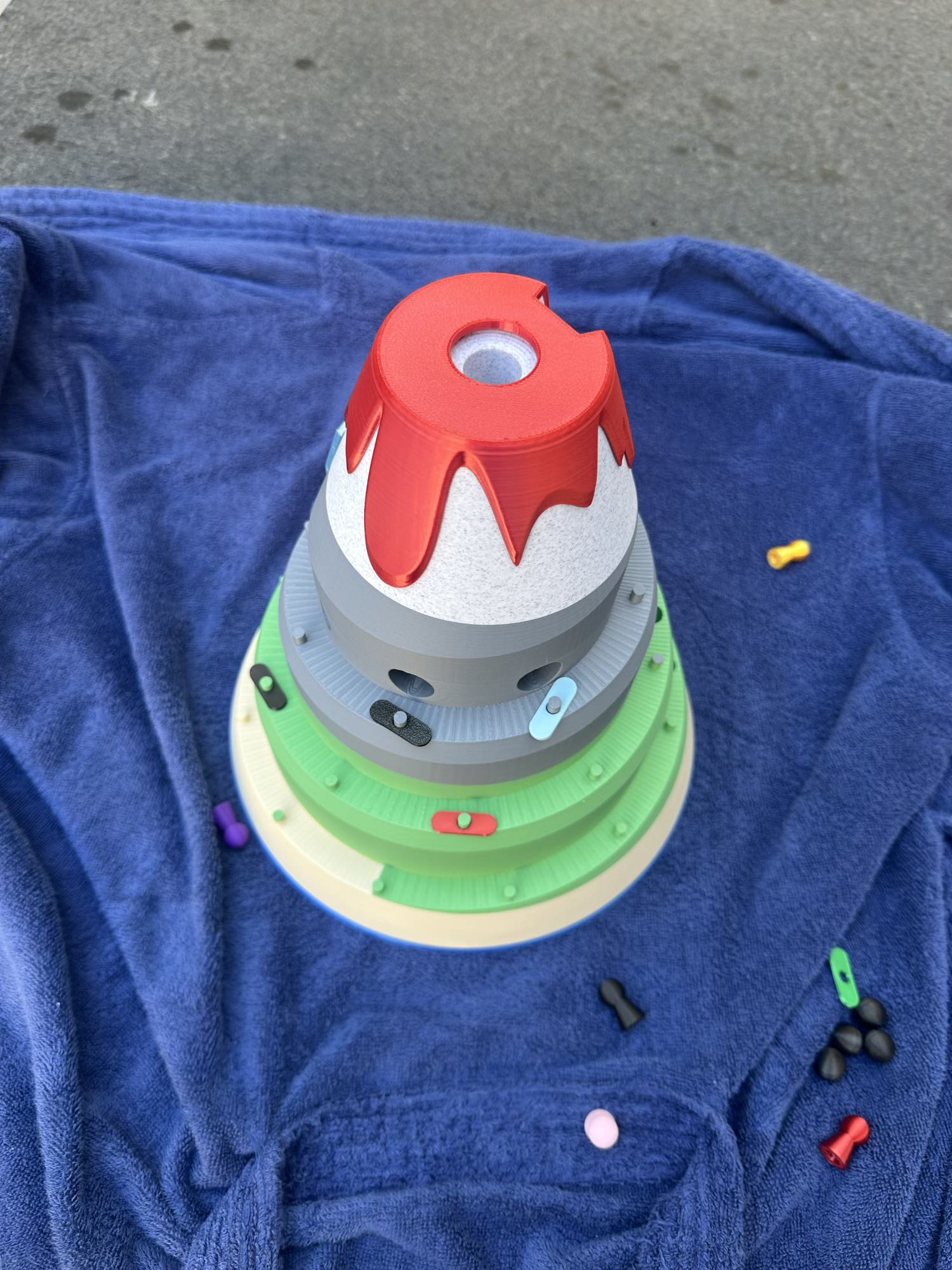 Top-down view of the Volcano Racer board game, showing colorful racing players climbing the layered volcano toward the red lava peak.