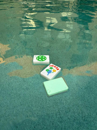 Pickleball Mahjong tiles floating in a pool demonstrating waterproof and pool-friendly design