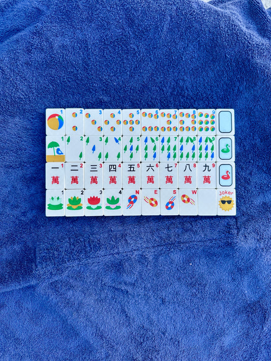 Close-up of floating Mahjong tiles with nautical pool-themed designs, including beach balls, lifebuoys, lotus flowers, and bamboo sticks, displayed on a towel.