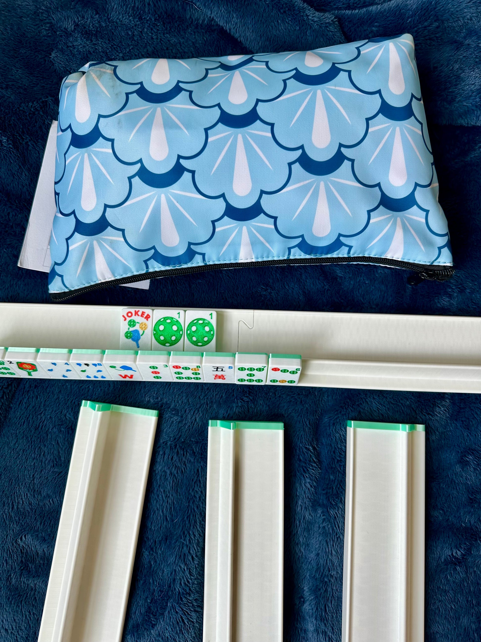 Blue and white patterned pouch on a dark blue surface with dice and game pieces.