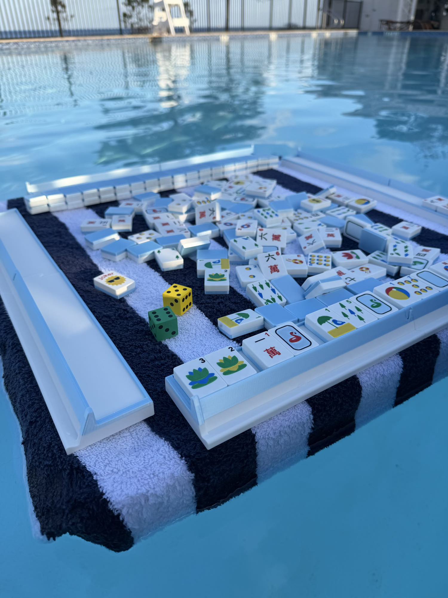 Full-size, light weight, portable floating Mahjong tiles with American-made game pieces arranged on a floating board floating in a swimming pool.
