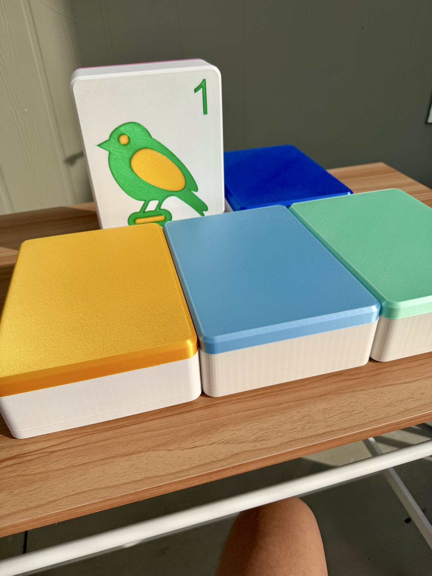 Colorful blocks with a card featuring a number and a bird on a wooden surface.