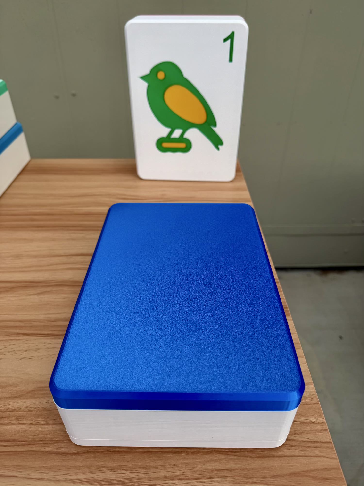 Blue and white tile box with a green bird card on a wooden surface