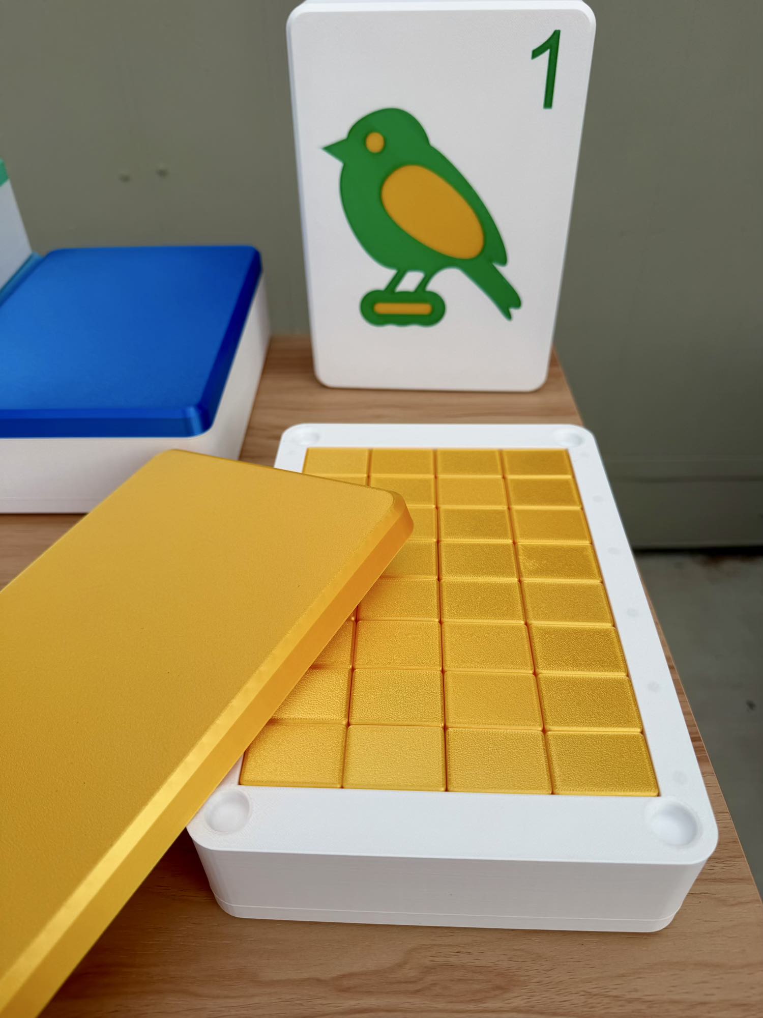 Yellow Mahjong Tiles in a container with a card featuring a green bird on a gray background