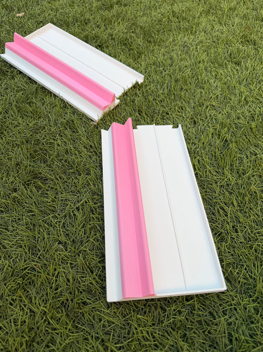 Two white portable Siamese Mahjong racks with pink rails, shown side-by-side on a grass surface.