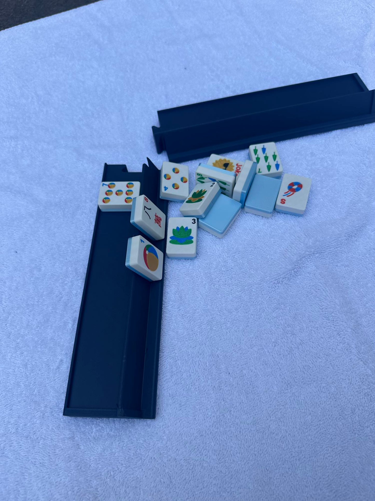 Set of American Mahjong Tiles Sitting Next to An American Mahjong Travel Rack That is Perfect for travel because it can split it two and fit in a small bag but also handle large tiles.