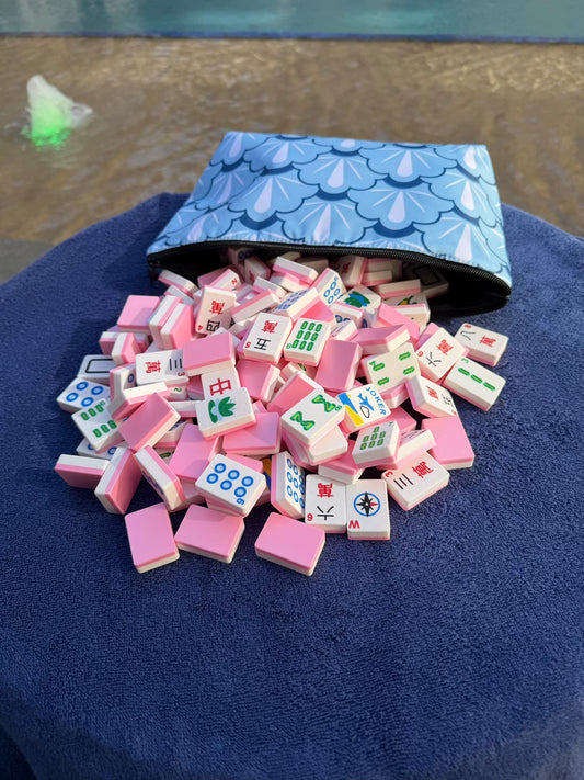 Spools Pink Compass mahjong tiles spilled from a carrying bag, showing pink tile backs and colorful compass-style faces.