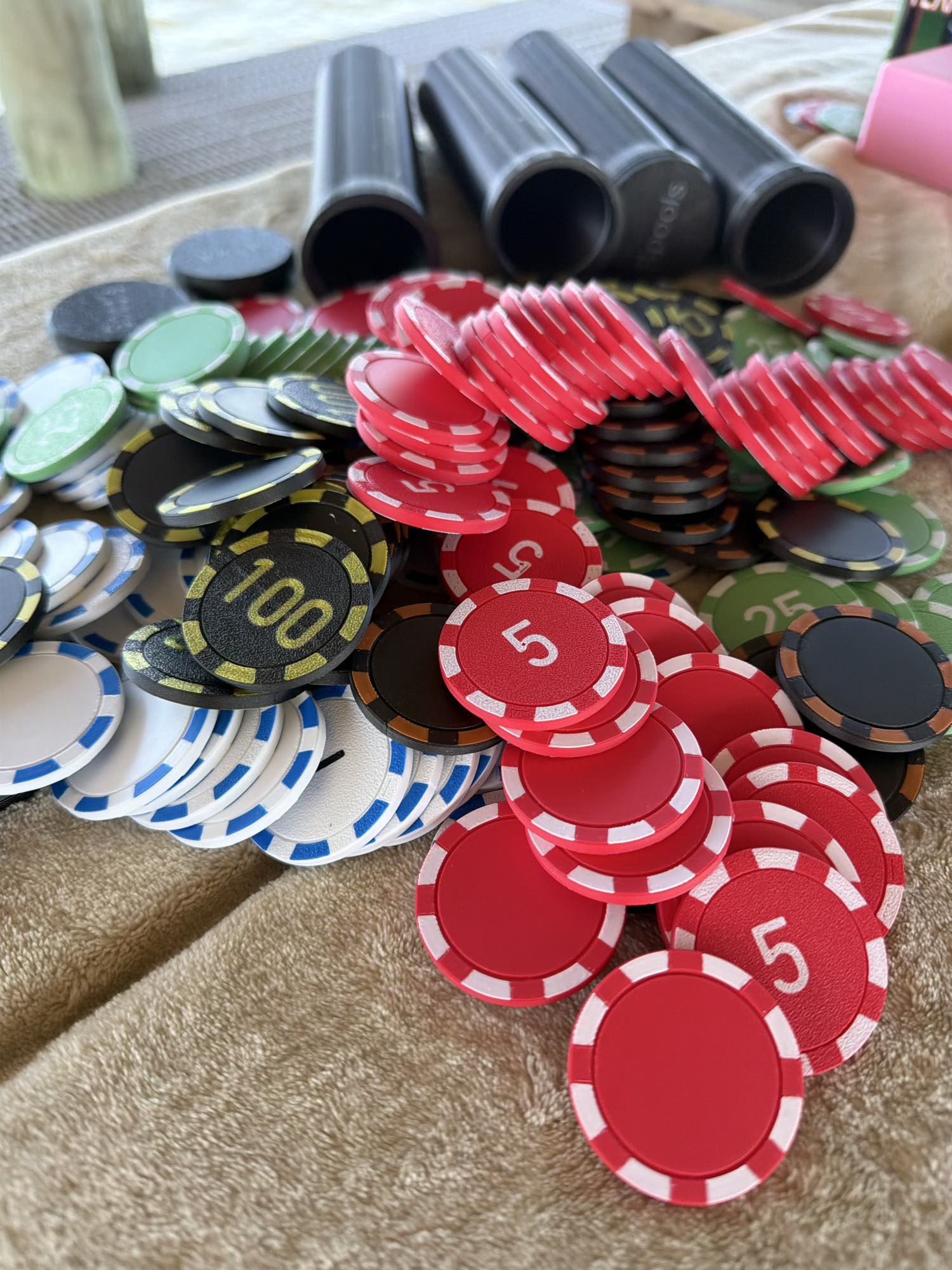 Spools lightweight poker chips spread out on a table showing color variety and textured surface.
