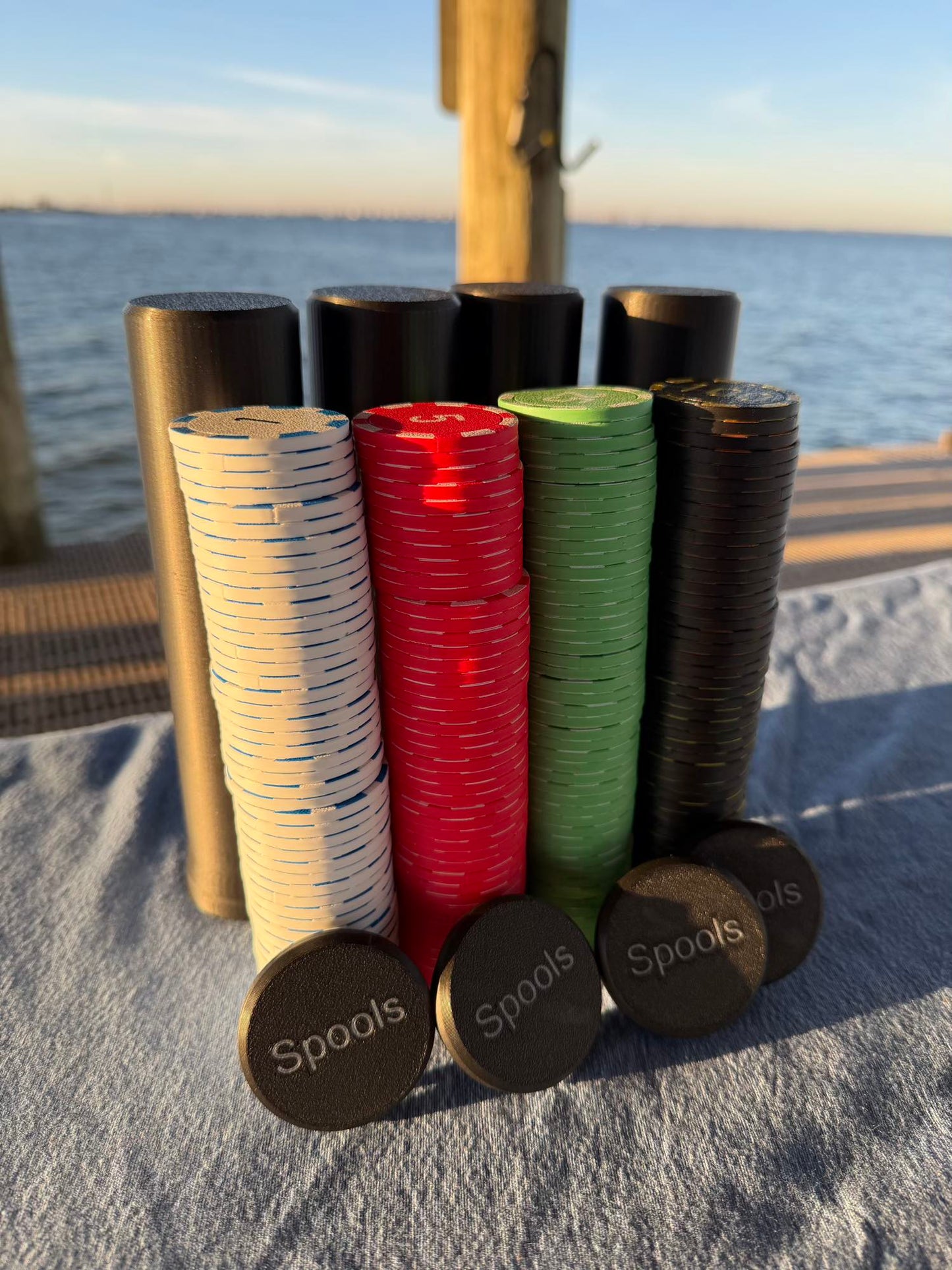 Spools lightweight poker chips arranged in stacks beside compact travel cases near the water.