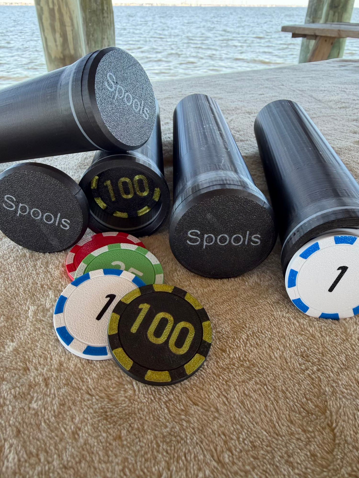 Spools poker chips with printed values displayed alongside compact black travel cases.
