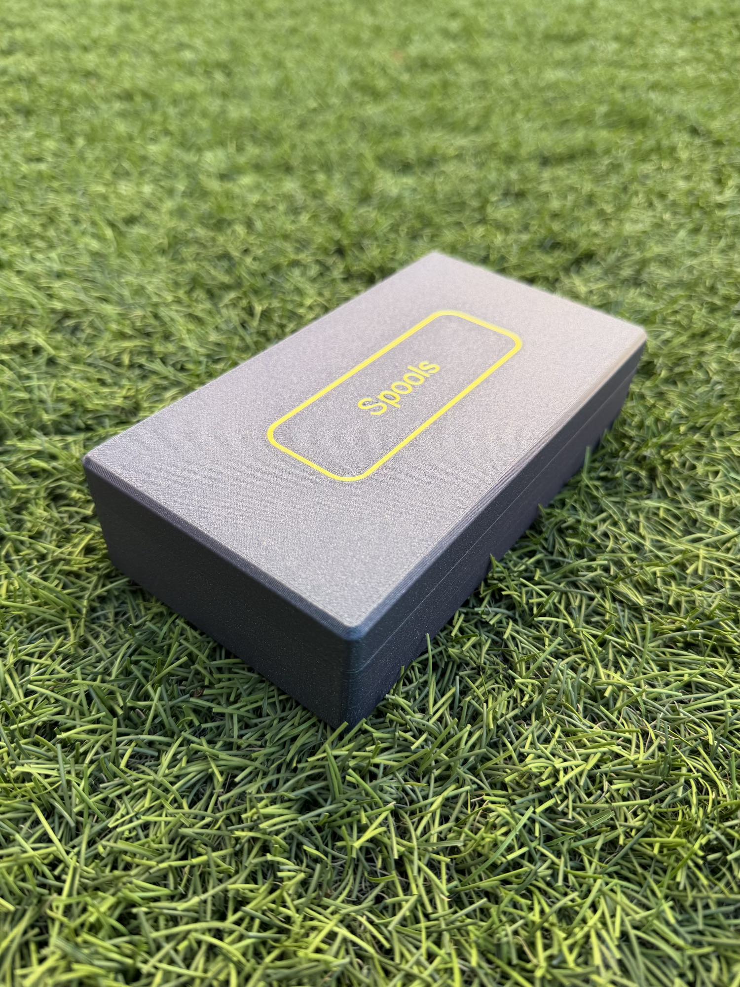 Spools travel poker set closed in a slim gray carrying case with yellow logo, shown on green grass.
