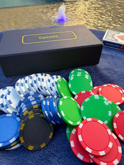 Spools travel poker set with lightweight poker chips spread out next to the case and a deck of cards by a pool.