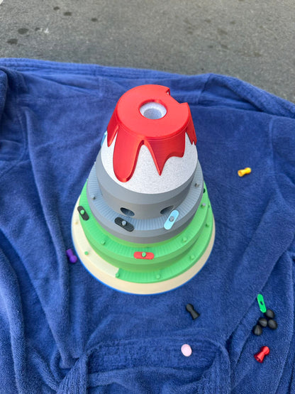 Top-down view of the Volcano Racer board game, showing colorful racing players climbing the layered volcano toward the red lava peak.
