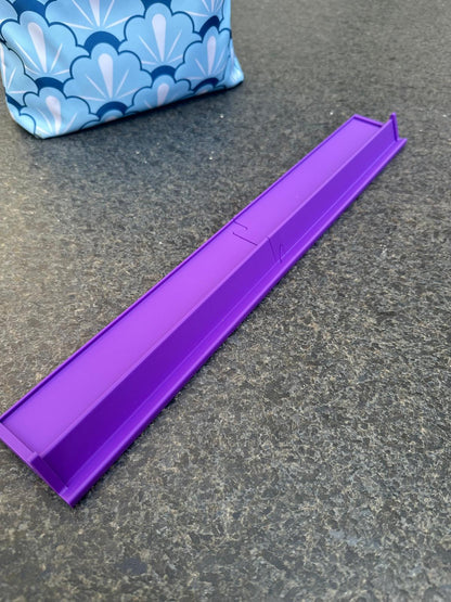 Purple mahjong rack for floating nautical-themed mahjong set, shown beside a blue patterned carrying bag.
