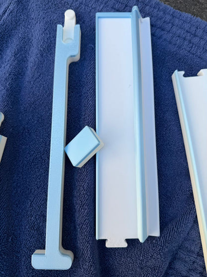 Overhead view of the blue Travel Mahjong rack and pusher components laid out on a navy towel.